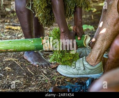 Newcomers to Bougainville are welcomed in an unusual way. With water from a bamboo cane the feet are washed to the island baptism. Island baptism as a blessing by indigenous people in Bougainville, Papua New Guinea
