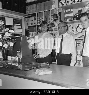 Johan Cruijff in his sports store  Johan Cruyff behind the checkout, all right Henny Cruyff Date: August 8, 1968 Location: Amsterdam, Noord-Holland Keywords: group portraits, sports stores Personal name: Cruyff, Henny, Cruyff, Johan Stock Photo