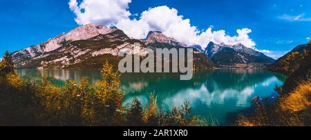 Beautiful mountain lake with blue sky and clouds. Mountains in the background with plants and stone Stock Photo