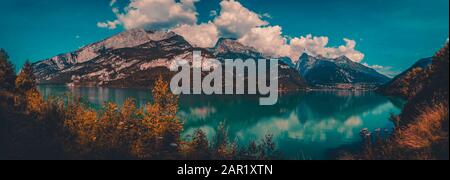 Beautiful mountain lake with blue sky and clouds. Mountains in the background with plants and stone Stock Photo