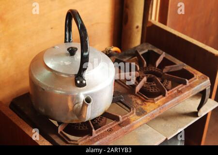 High angle shot of an old silver kettle on a rusted stove Stock Photo
