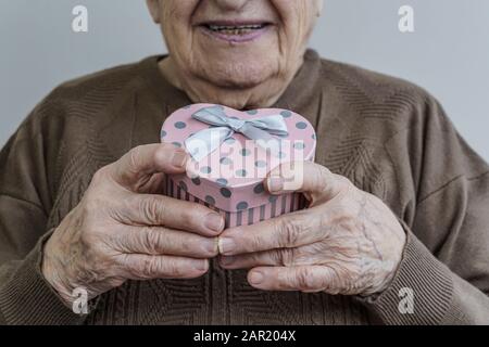 A happy senior woman holding a heart shaped gift Stock Photo