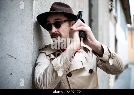 Detective taking cover and aiming with his handgun Stock Photo