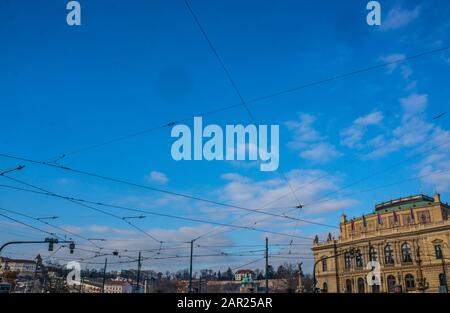 Tram line power cords hanging over square at Galerie Rudolfinum in Prague. Tangled electrical supply for public transport purposes with blue sky Stock Photo
