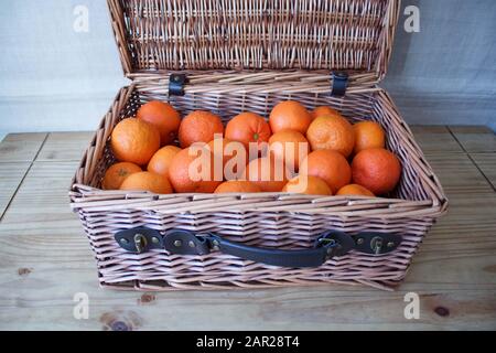 Fresh Oranges in Hamper Basket on Wooden Table Stock Photo