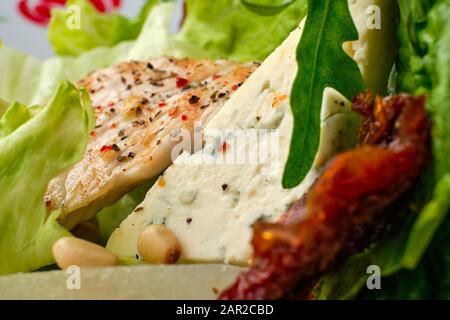 Macro photo of salad with roasted turkey, dried tomato, gorgonzola, canned pear and pine nuts Stock Photo