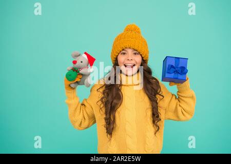 small girl hold mouse toy and present box. child knitted clothes play with toy rat. toy shop for kids. christmas is here. xmas favorite winter holiday. happy new 2020 year. cute santa mice toy gift. Stock Photo