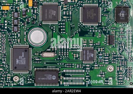 Green digital circuit board of computer harddrive showing metal printed circuits and chips Stock Photo