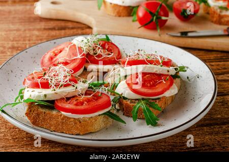 Open sandwiches with fresh mozzarella, tomatoes and arugula. Italian food concept Stock Photo