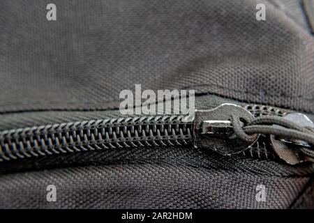 A close-up view of a black zipper shows the teeth and detail of its stitching into the fabric of a backpack. Stock Photo