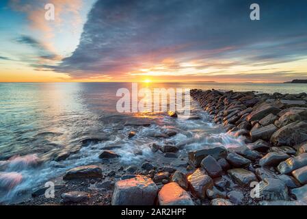 Dramatic winter sunset over a rocky outcrop at Kimmeridge Bay on the Dorset coastline Stock Photo