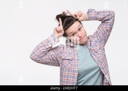 Funny young woman grimacing showing bull horns on head. Positive facial human emotion. Stock Photo