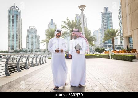 Two businessmen with traditional emirates clothes meeting in Dubai ...