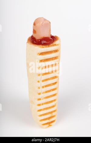 Tasty French hot dog with ketchup. A hot snack sold at gas stations. Light background. Stock Photo