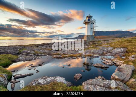 Sunset over Rhue Lighthouse reflected in a rock pool near Ullapool in the Highlands of Scotland Stock Photo