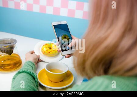 Closeup of women's hands making photo of donut with tea Stock Photo