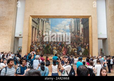 Visitors in front of The Wedding Feast at Cana by Italian artist Paolo Veronese in Denon Wing of Louvre Museum (Musée du Louvre) in Paris, France Stock Photo