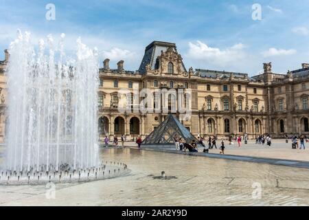 Fountain next to entrance Pyramid on Cour Napoléon (courtyard) with Richelieu Wing in background, Louvre Museum (Musée du Louvre), Paris, France Stock Photo