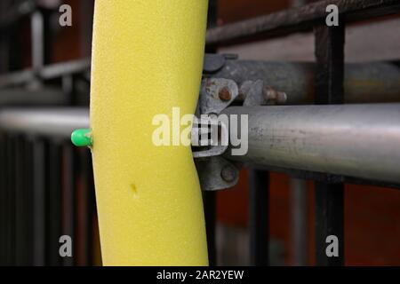 Close-up of a scaffolding joint on a building in Victoria, central London, with a scaffold protection foam tubing cover surrounding an upright pole. Stock Photo