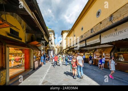 Tourists shop the jewelry stores and gift shops of the Ponte Vecchio in Florence Italy in the late afternoon as a storm develops over head.. Stock Photo