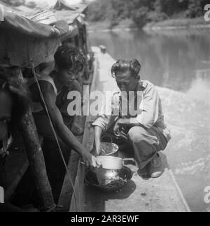 [Patrol boat on a river. Two native soldiers prepare a meal] Date: 1947/01/01 Location: Indonesia, Dutch East Indies Stock Photo