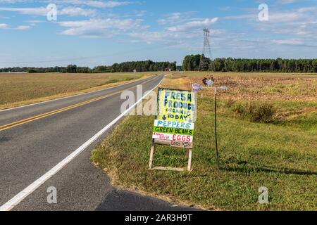 A handmade sign advertising farm products on the side of a country road. Stock Photo