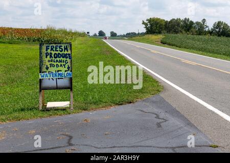 A handmade sign advertising farm products on the side of a country road. Stock Photo