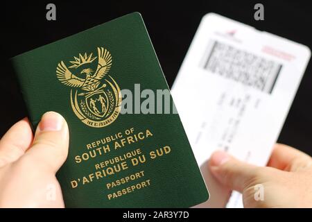 High angle shot of a person holding a passport and a plane ticket over a black background Stock Photo