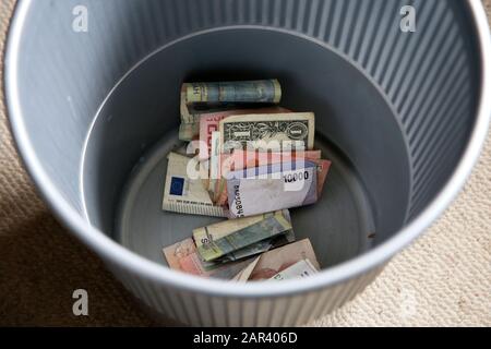High angle shot of some cash in a metal garbage can on a carpet Stock Photo