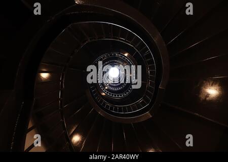 Round rolling staircase with a light shining in the end Stock Photo