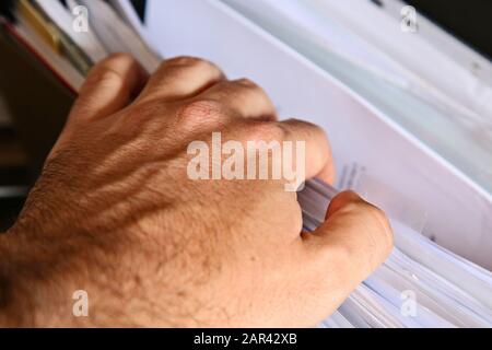 A Caucasian man looking inside a filing cabinet for tax records. Stock Photo