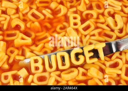 Alphabet spaghetti spelling budget with random letters in tomato sauce background Stock Photo