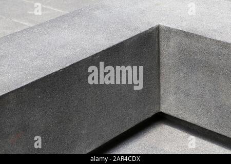 A seat in the park that looks like a right angle. The seat is made of cement. Stock Photo