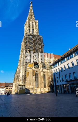 Ulm, Germany, December 29, 2019, Ancient tall minster, gothic cathedral church building with tall steeple in old town with scaffolding, a tourist magn Stock Photo