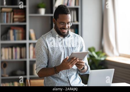 Smiling african business man using digital tablet computer in office Stock Photo