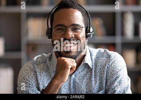 Smiling african man professional telemarketer wear headset look at camera Stock Photo