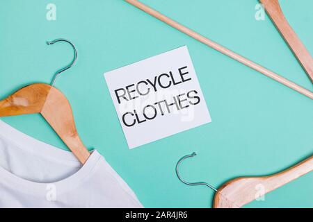 White t-shirts on wooden hangers lying on ponk background, top view Stock Photo