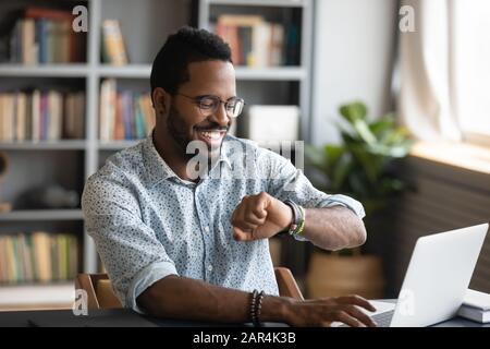 Happy african businessman worker looking at smart watch at work Stock Photo