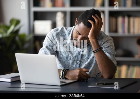 Tired bored african employee falling asleep sitting at work desk Stock Photo