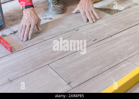 Man installing rectangular shaped floor tiles in kitchen. Applying ...