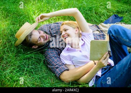 Couple in love spend leisure reading book. Man and girl lay on grass relaxing. Romantic couple family enjoy leisure with poetry or literature grass background. Couple soulmates at romantic date. Stock Photo