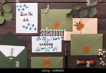 Wedding invitations, envelopes, branches, cards on wooden table Stock Photo