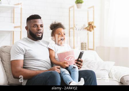 Emotional black father and daughter watching movies together Stock Photo