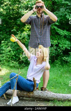 Observing nature concept. Couple ornithologists expedition in forest. Couple enjoy hike in forest observing nature. Woman and man looking binoculars near bonfire. Ornithology interesting occupation. Stock Photo