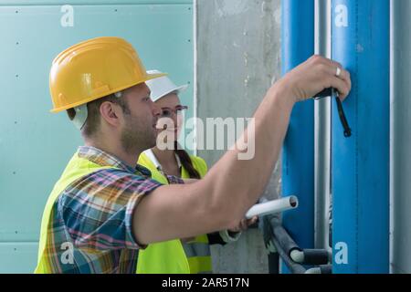 Construction workers measuring pipes on site Stock Photo