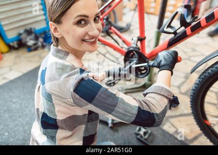Happy woman working as a bicycle mechanic Stock Photo