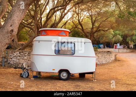 Tiny little caravan with orange sliding roof on camp ground Stock Photo