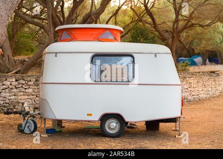 Tiny little caravan with orange sliding roof on camp ground Stock Photo