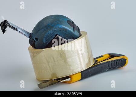 old transparent adhesive tape, measuring tape, clerical knife on a white background stacked in a pile.