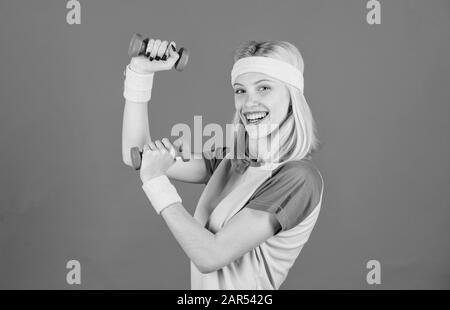 Ultimate upper body workout for women. Fitness instructor hold little dumbbell blue background. Fitness concept. Girl exercising with dumbbell. Workout with dumbbell. Beginner dumbbell exercises. Stock Photo